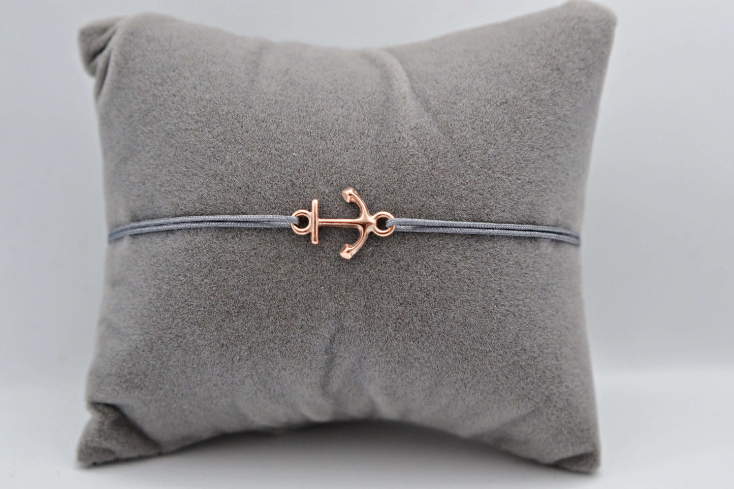 Roségoldenes Anker Armband mit grauem Bank auf einem grauen Schmuckkissen