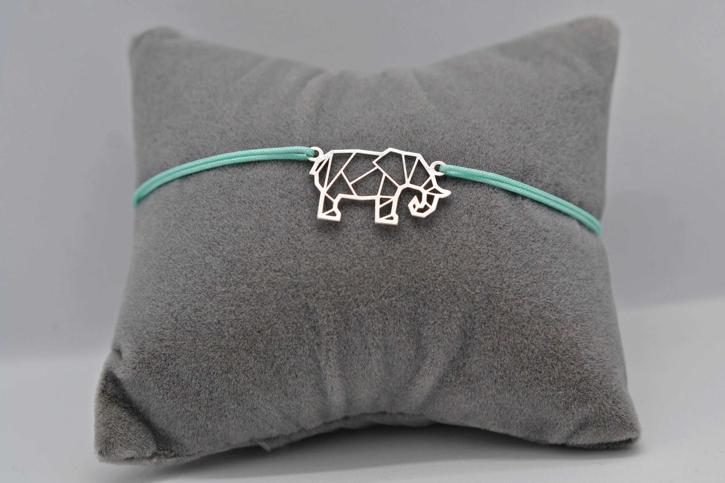Elefanten Armband in silber mit mintgrünem Band auf einem grauen Schmuckkissen