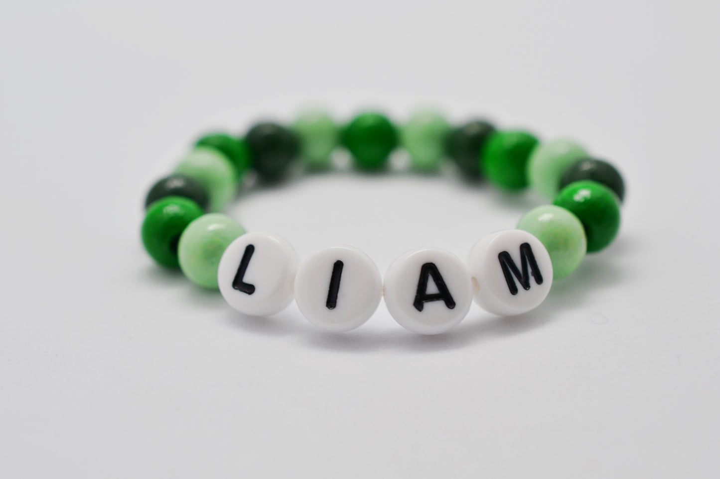 Personalisierbares Baby Armband mit Namen "Liam" und Holzperlen in Grüntönen