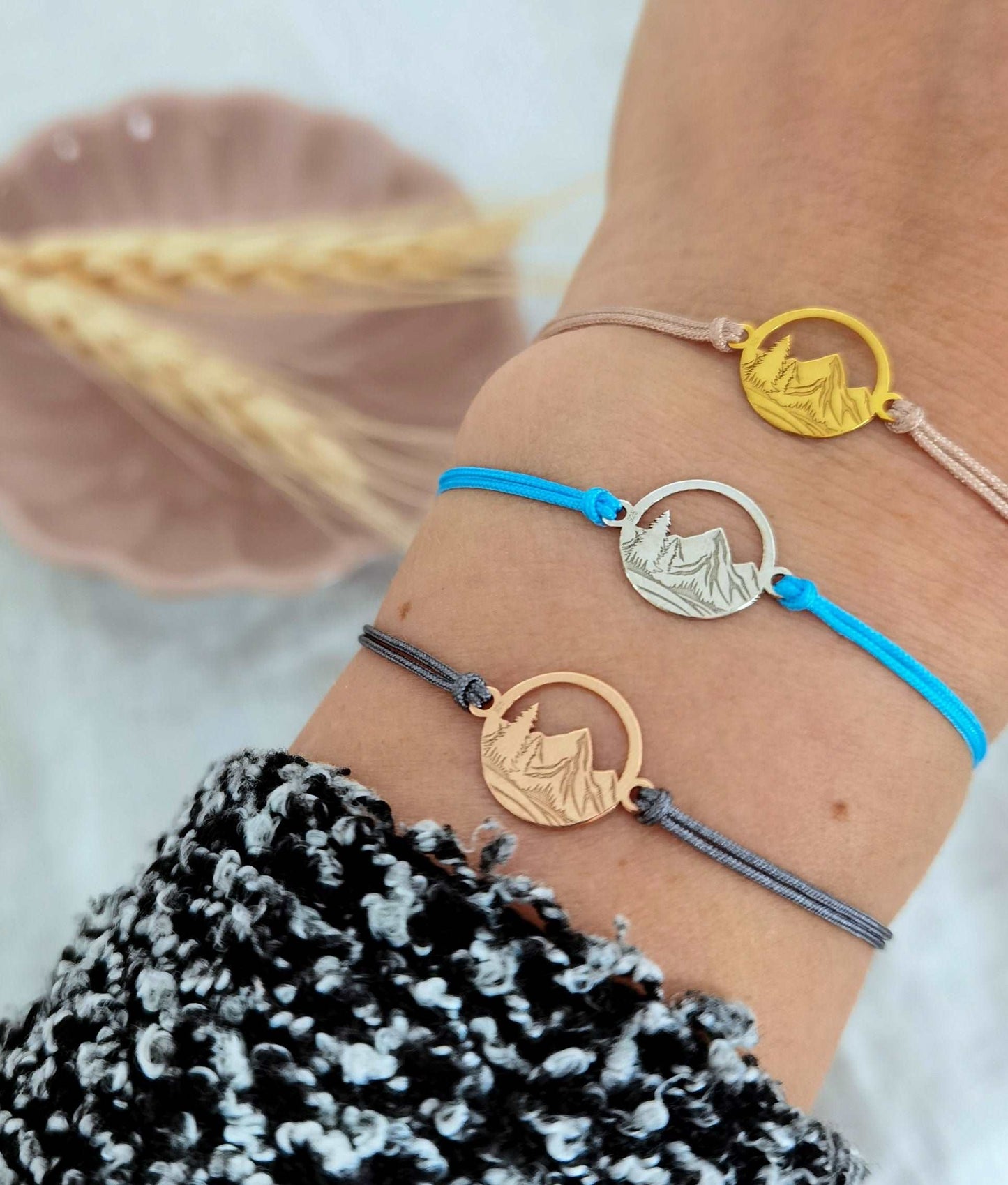 Tragefoto 3x Berg Armband aus Sterling Silber am Handgelenk einer Frau. Untere Armband graues Band und roségoldener Berg, mittleres Armband türkises Band und silberner Berg, oberes Armband beiges Band und goldener Berg