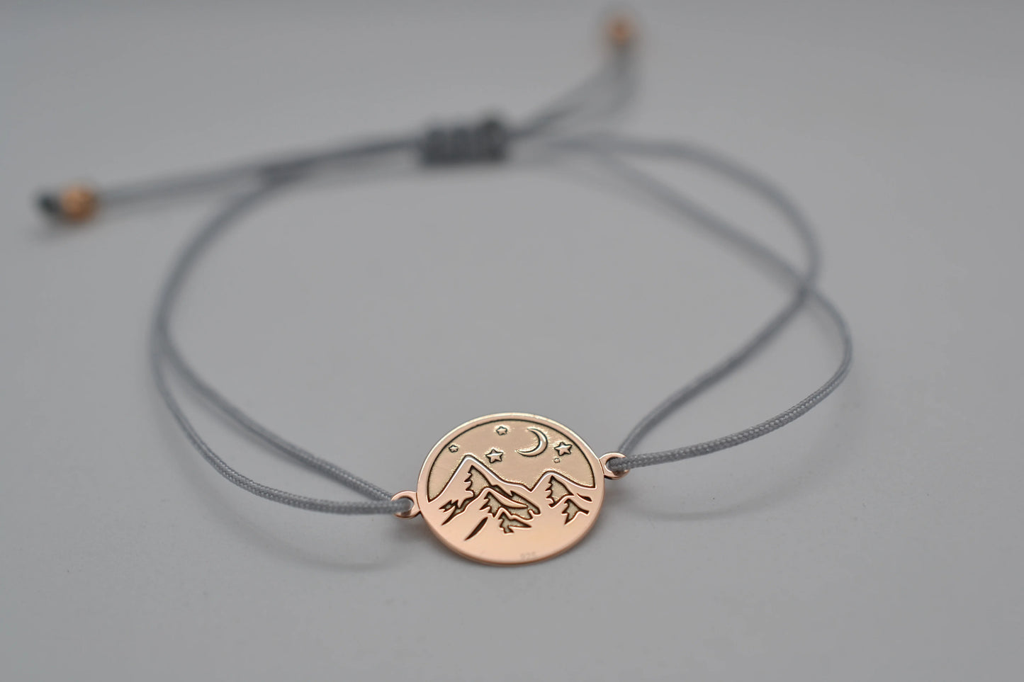 Nahaufnahme roségoldenes Berg Armband mit grauem Band