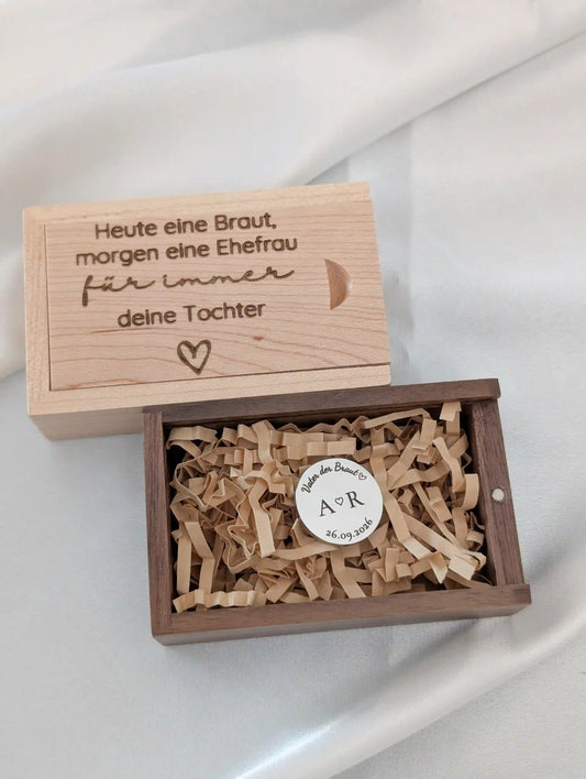 Goldener Anstecker zur Hochzeit in geöffneter Holzbox mit hellem Holzwolle-Inlay, gravierter Deckel mit persönlichem Text