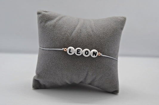 Personalisiertes Namensarmband mit Namen "Leon" auf einem grauen Schmuckkissen fotografiert