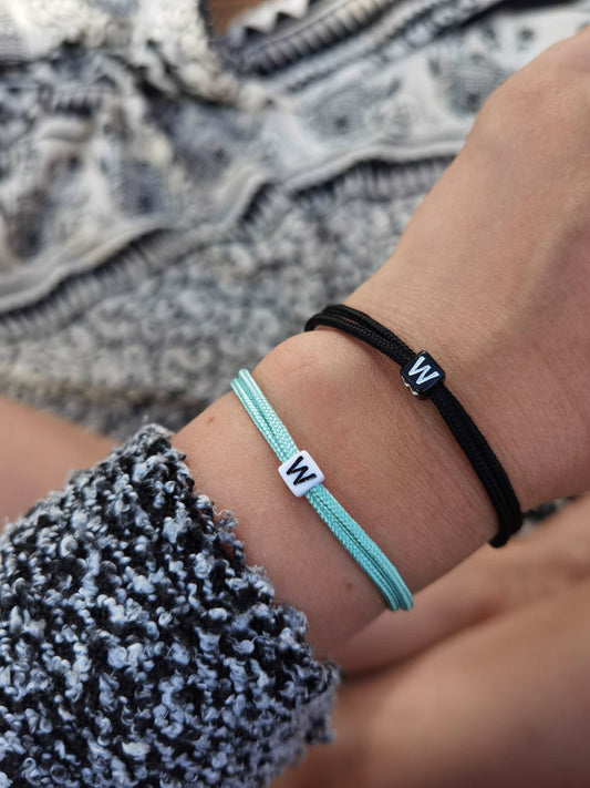 Tragefoto Surfer Armband personalisiert ein mintgrünes Armband mit weißer Buchstabenperle "W" und ein schwarzes Armband mit schwarzer Buchstabenerle "W"