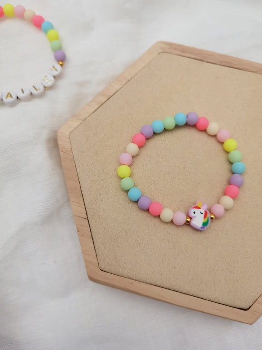 Einhorn Armband mit pastellfarbenen Perlen auf einem Holz Sechseck