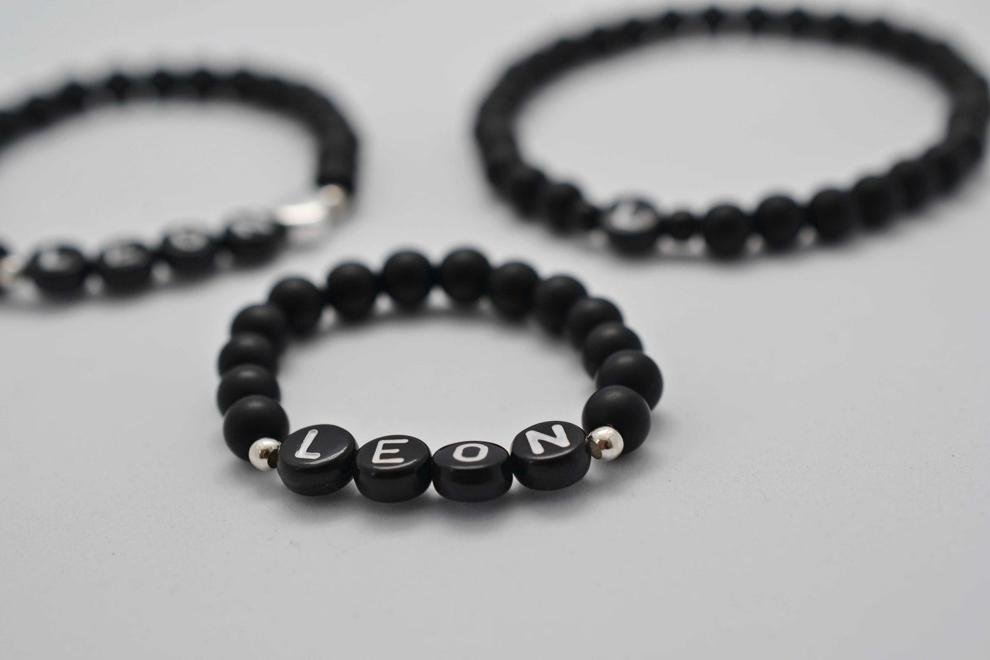 Drei personalisierte schwarze Familienarmbänder als Geschenkidee für junge Familien