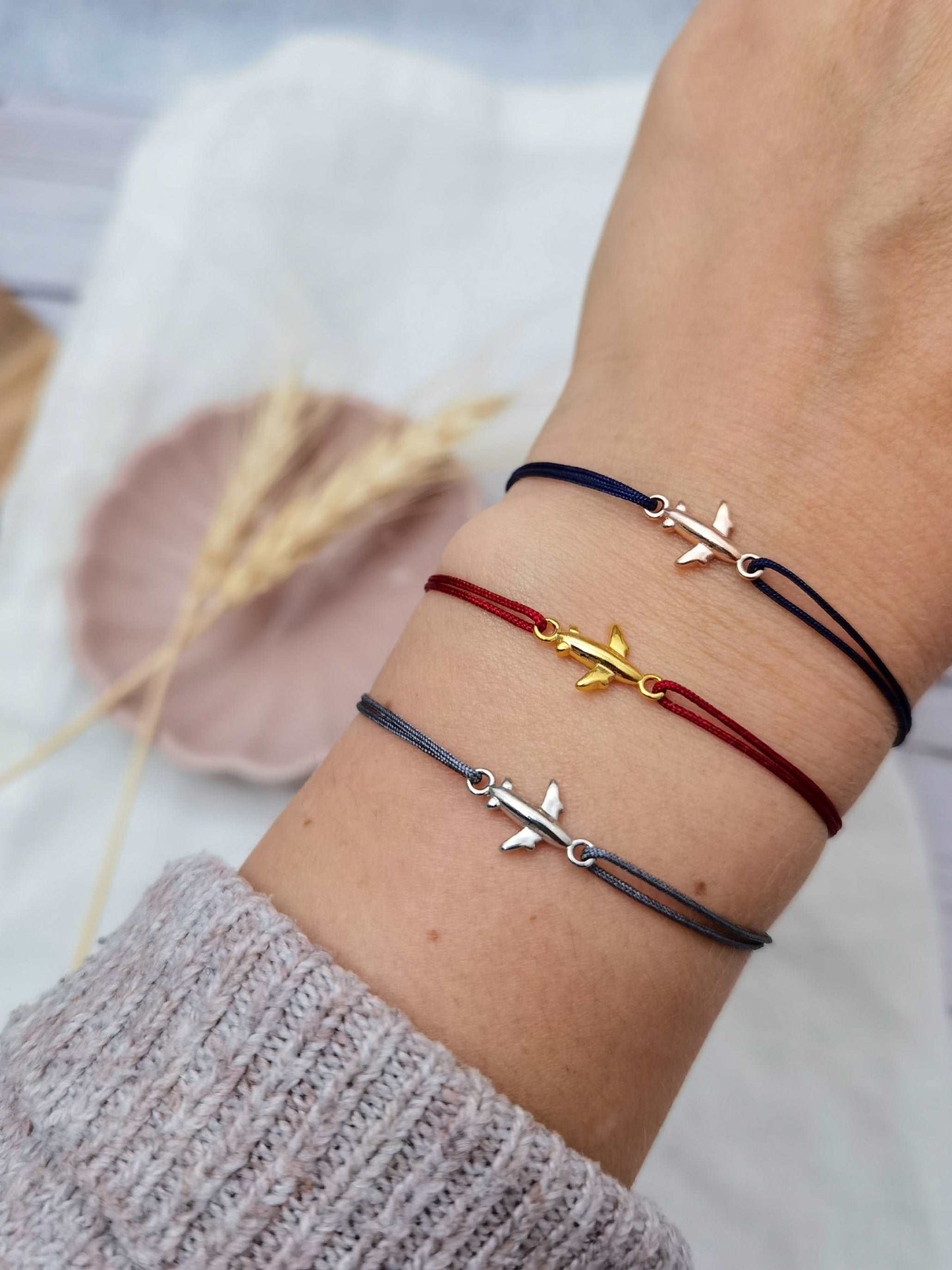 Tragefoto von drei Flugzeug Armbändern. Unteres Armband in silber und grau, mittleres Armband in rot und gold, oberes Flugzeug Armband in roségold und blau