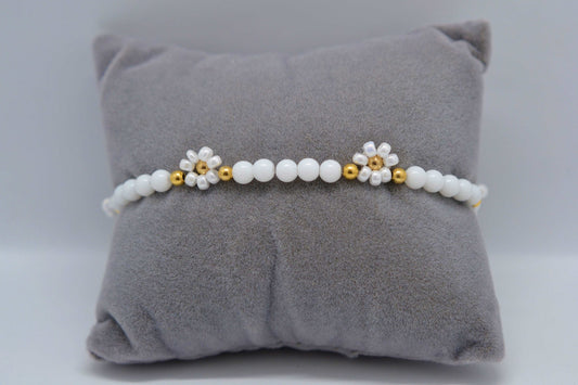 Gänseblümchen Armband in weiß und gold auf einem grauen Schmuckkissen fotografiert