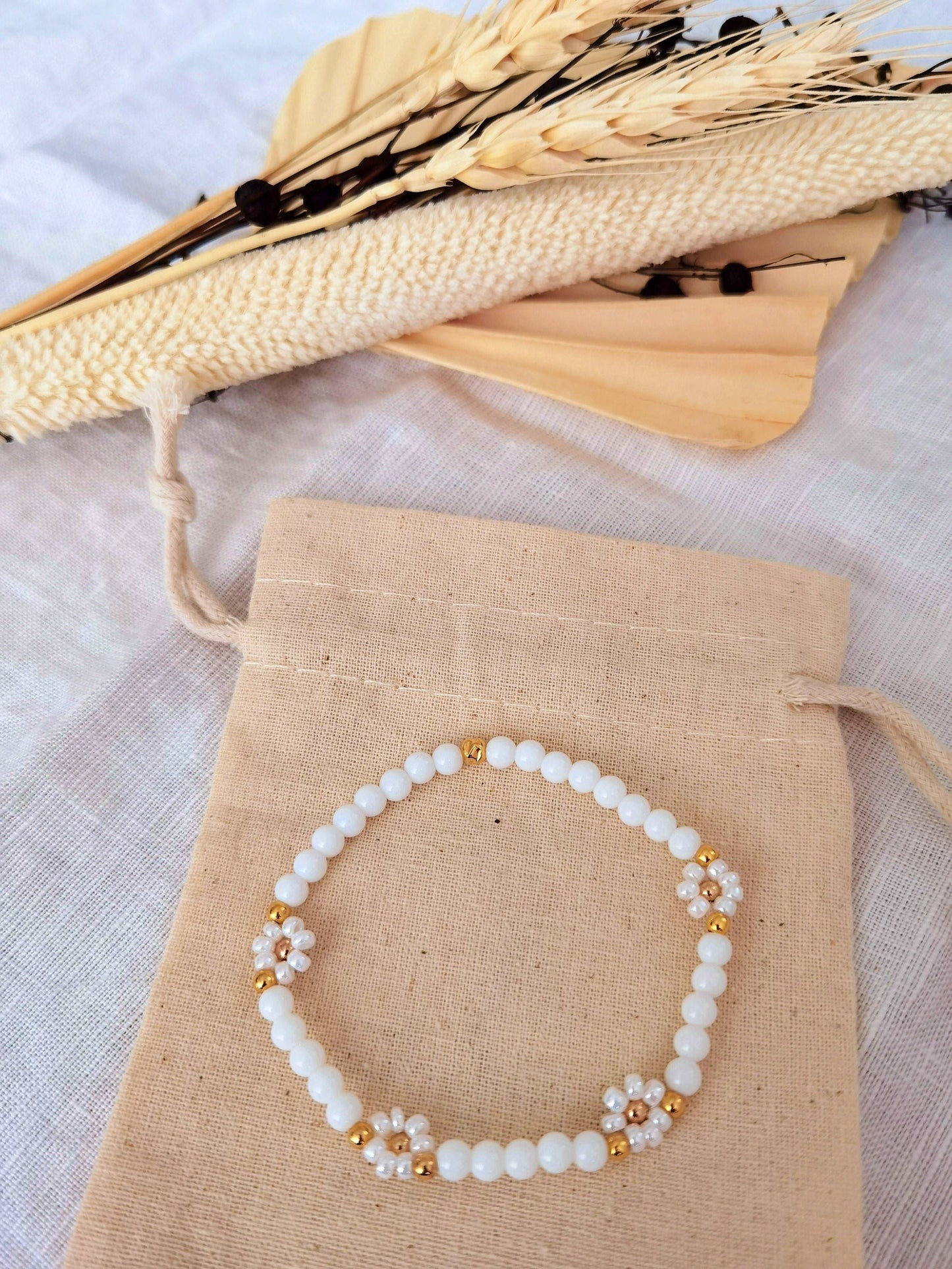 Gänseblümchen Armband in weiß und gold auf einem Leinensäckchen