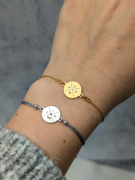 Tragefoto zwei Gravurarmbänder. Ein Armband mit silbernem Gravurplättchen und grauem Band und ein goldenes Gliederarmband