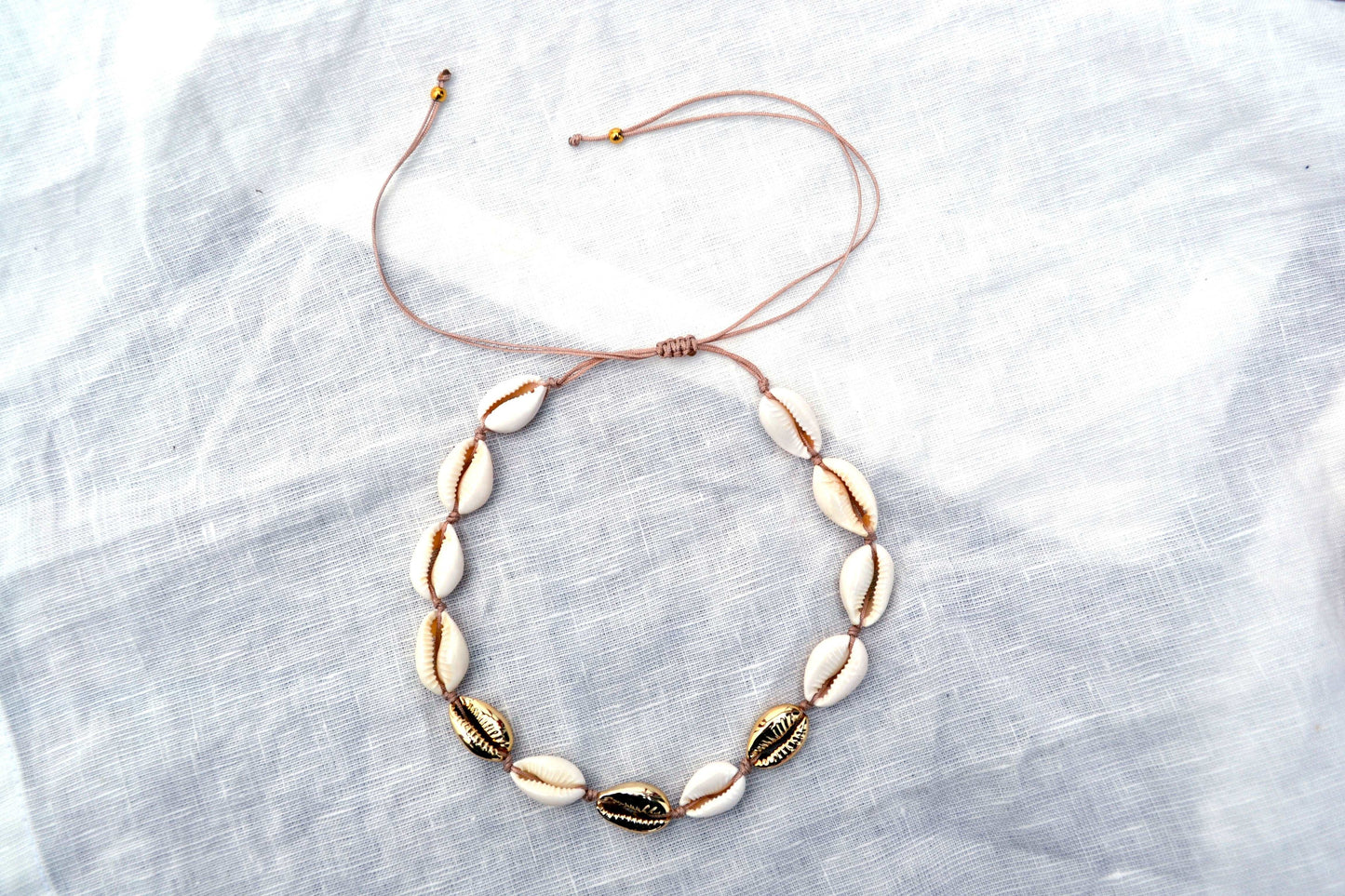 Kauri Muschel Choker mit weißen und goldenen Muscheln und einem beigen Band
