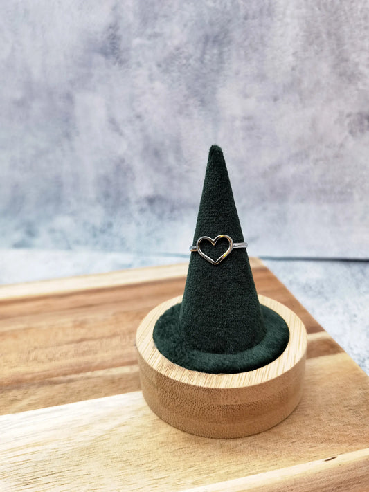 silberner Herzring fotografiert auf einem dunkelgrünen samt Ringhalter mit Holzfuß