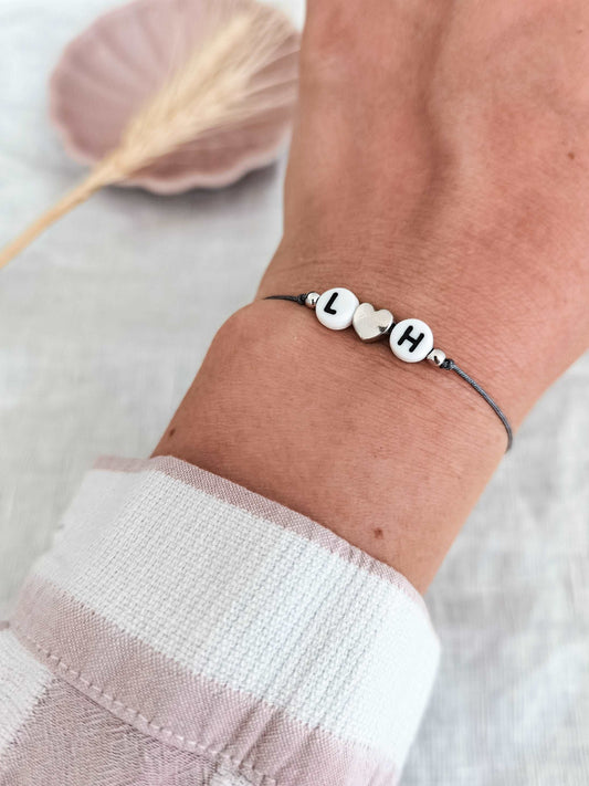 Tragefoto personalisiertes Initialenarmband mit Herz 925 aus Sterling Silber. Armband mit grauem Band und den Buchstaben L und H