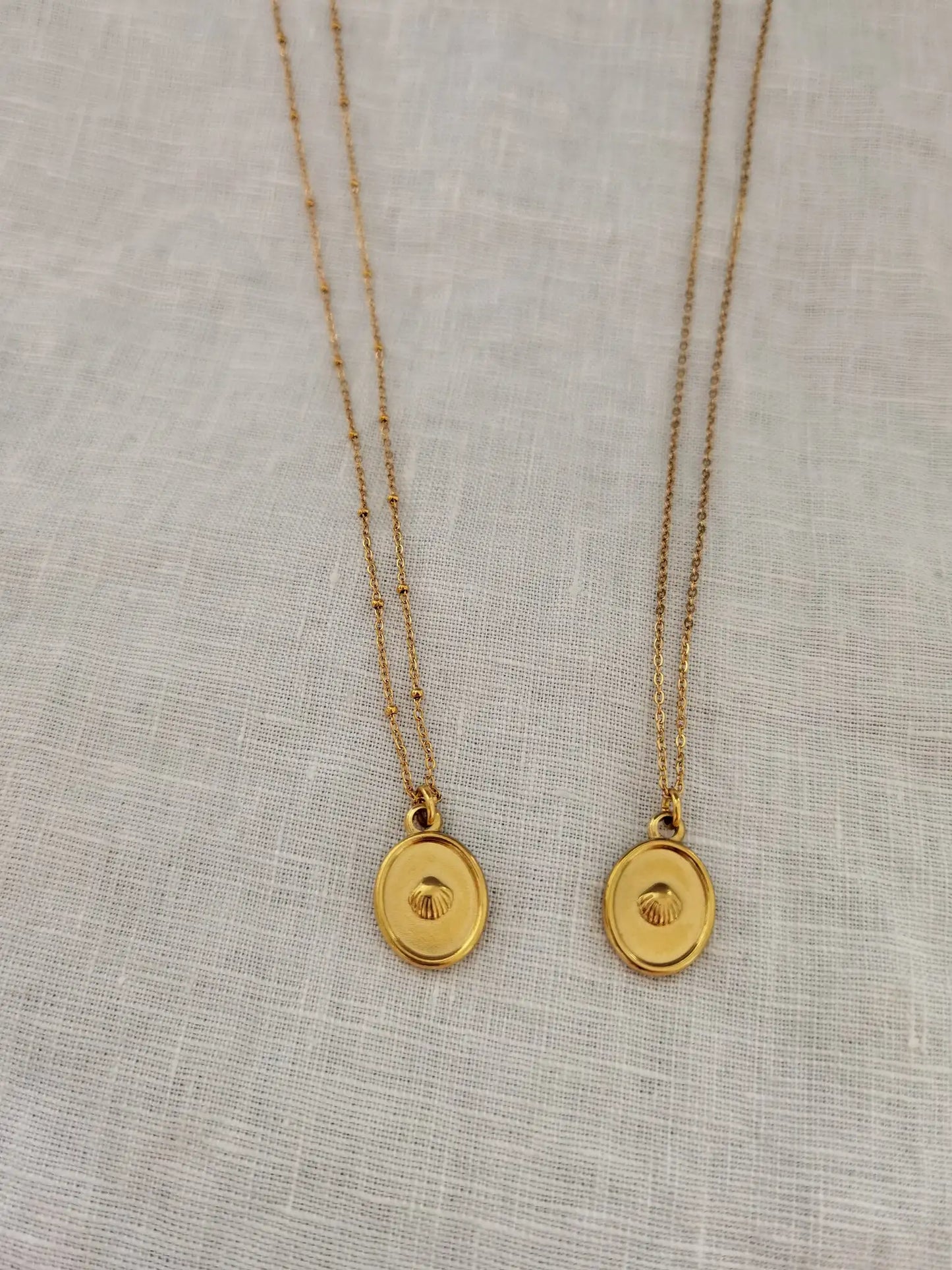 Zwei goldene Muschelkette aus Edelstahl auf weißem Hintergrund