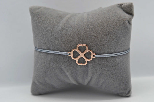 Kleeblatt Armband in roségold mit grauem Band auf grauem Schmuckkissen