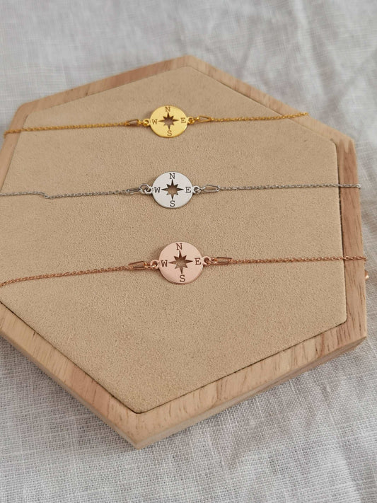 Kompass Armband in roségold, silber und gold auf einem Holz Sechseck
