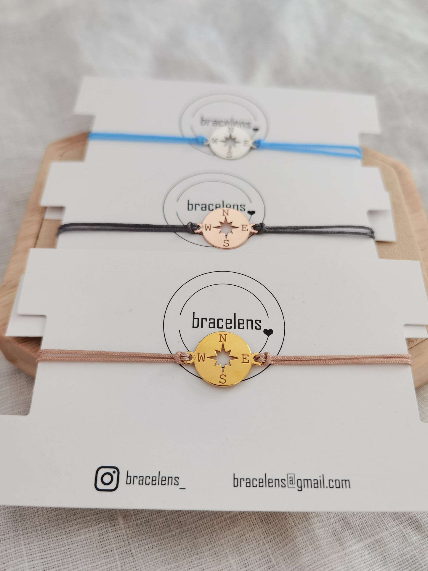 Kompass Armband gold mit beigem Band, roségold mit grauem Band und silber mit hellblauem Band jeweils auf einer weißen Schmuckkarte