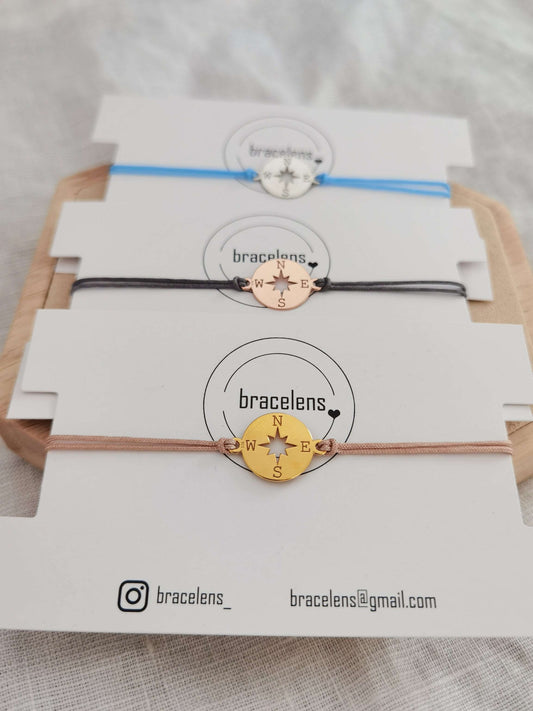Kompass Armband gold mit beigem Band, roségold mit grauem Band und silber mit hellblauem Band jeweils auf einer weißen Schmuckkarte