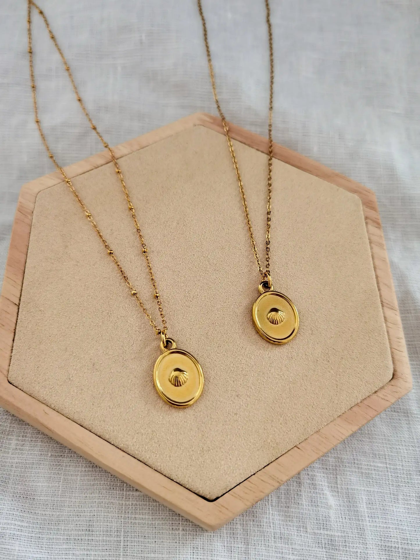 Zwei goldene Muschelkette aus Edelstahl auf einem Holz Sechseck