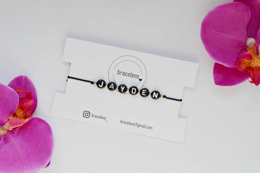 Personalisiertes Buchstabenarmband mit schwarzem Band, kleinen roségoldenen Perlen und der Aufschrift "Jayden" in schwarzen Buchstabenperlen geschrieben