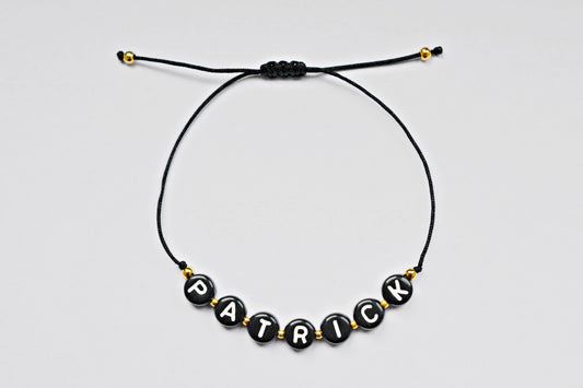 Personalisiertes Buchstabenarmband mit schwarzem Band, schwarzen Buchstabenperlen und kleinen goldenen Perlen - Aufschrift "Patrick" - ideal als Freundschaftsarmband