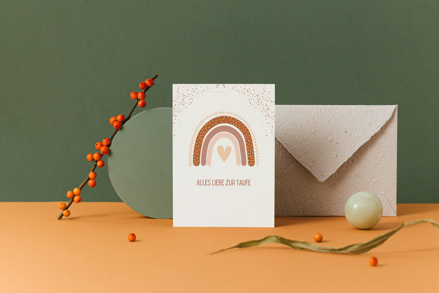 Postkarte zur Taufe mit Aufschrift "Alles Liebe zur Taufe" und einem Regenbogen in Brauntönen vor grünem Hintergrund