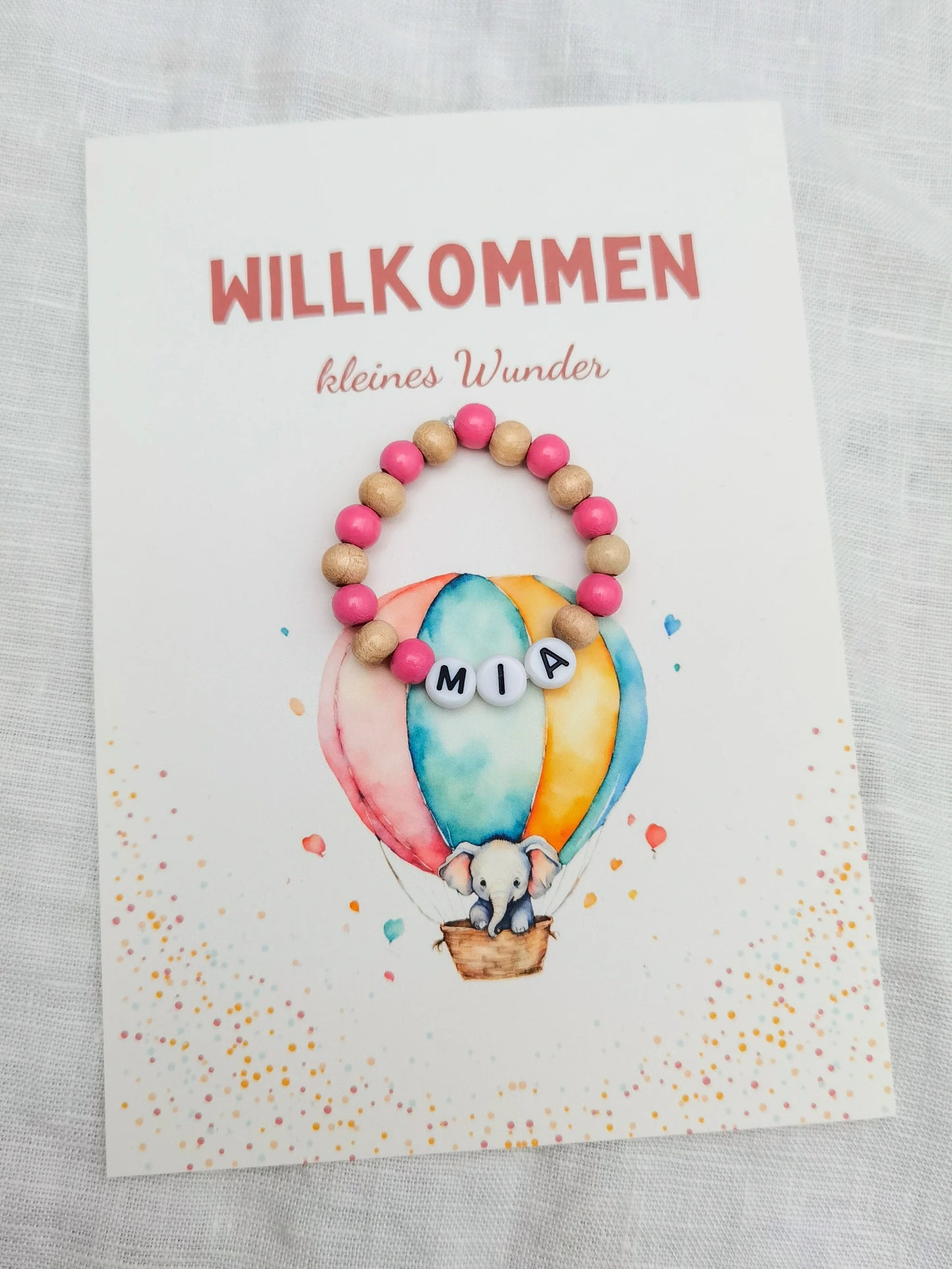 Postkarte "Willkommen kleines Wunder" mit Aufdruck Elefant im Heißluftballon und einem Baby Armband in rosa/natur