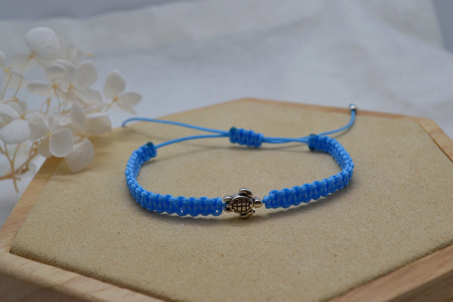 Nahaufnahme hellblaues Makramee Armband mit silberner Schildkröte