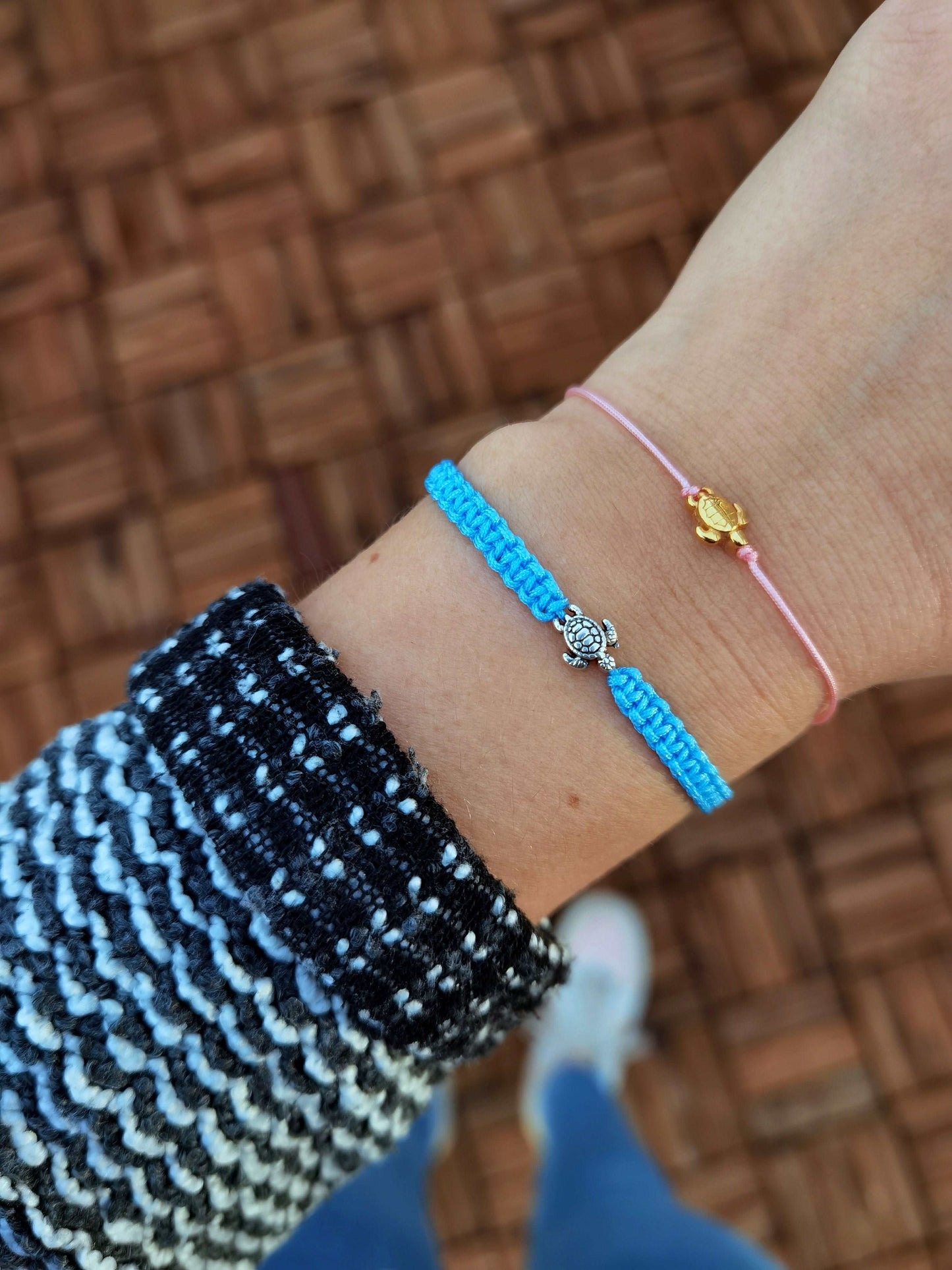 Tragefoto zwei Schildkröten Armbänder unteres Armband hellblau und silber mit Makramee Flechtung, oberes Armband rosa und gold ohne Flechtung