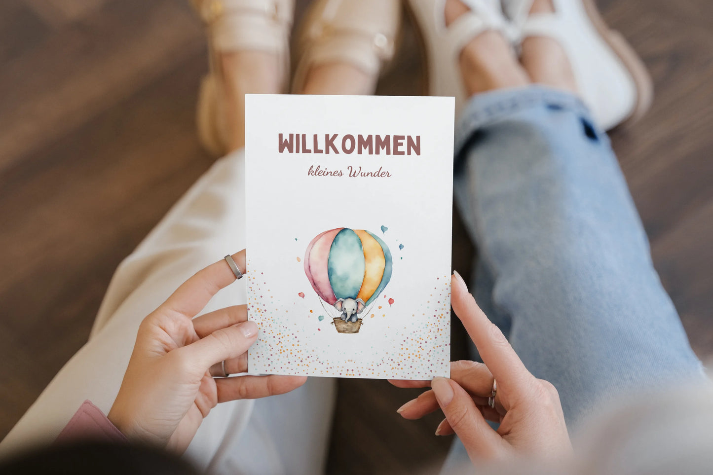 Postkarte Willkommen kleines Wunder mit einem süßen Elefanten in einem Heißluftballon wird in den Händen gehalten