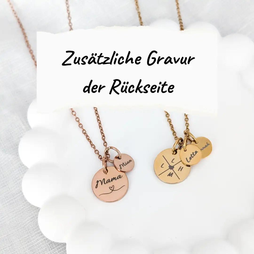 Eine roségoldene und eine goldene Gravurkette liegen nebeneinander auf einem weißen Schmuckuntersetzer. Darüber der Text "Zusätzliche Gravur der Rückseite"
