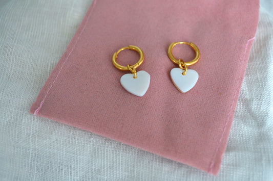 Goldene Edelstahl Creolen mit Herz Anhänger vor rosa Hintergrund