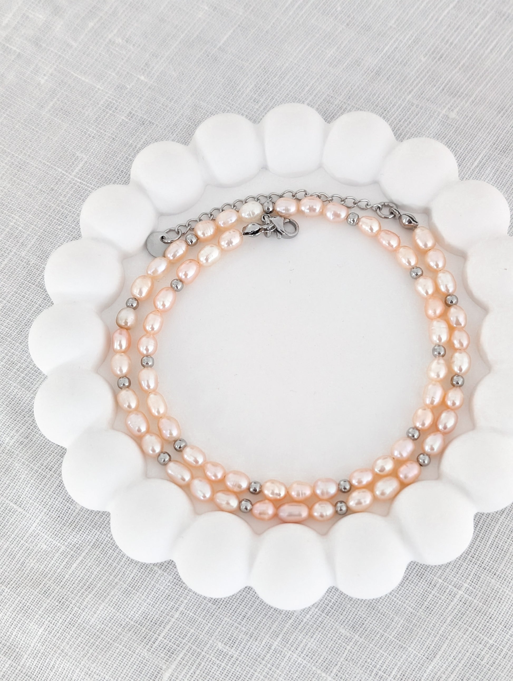 Rosa Süßwasserperlenkette mit silbernen Akzenten aufgerollt in einem weißen Bubble Untersetzer fotografiert