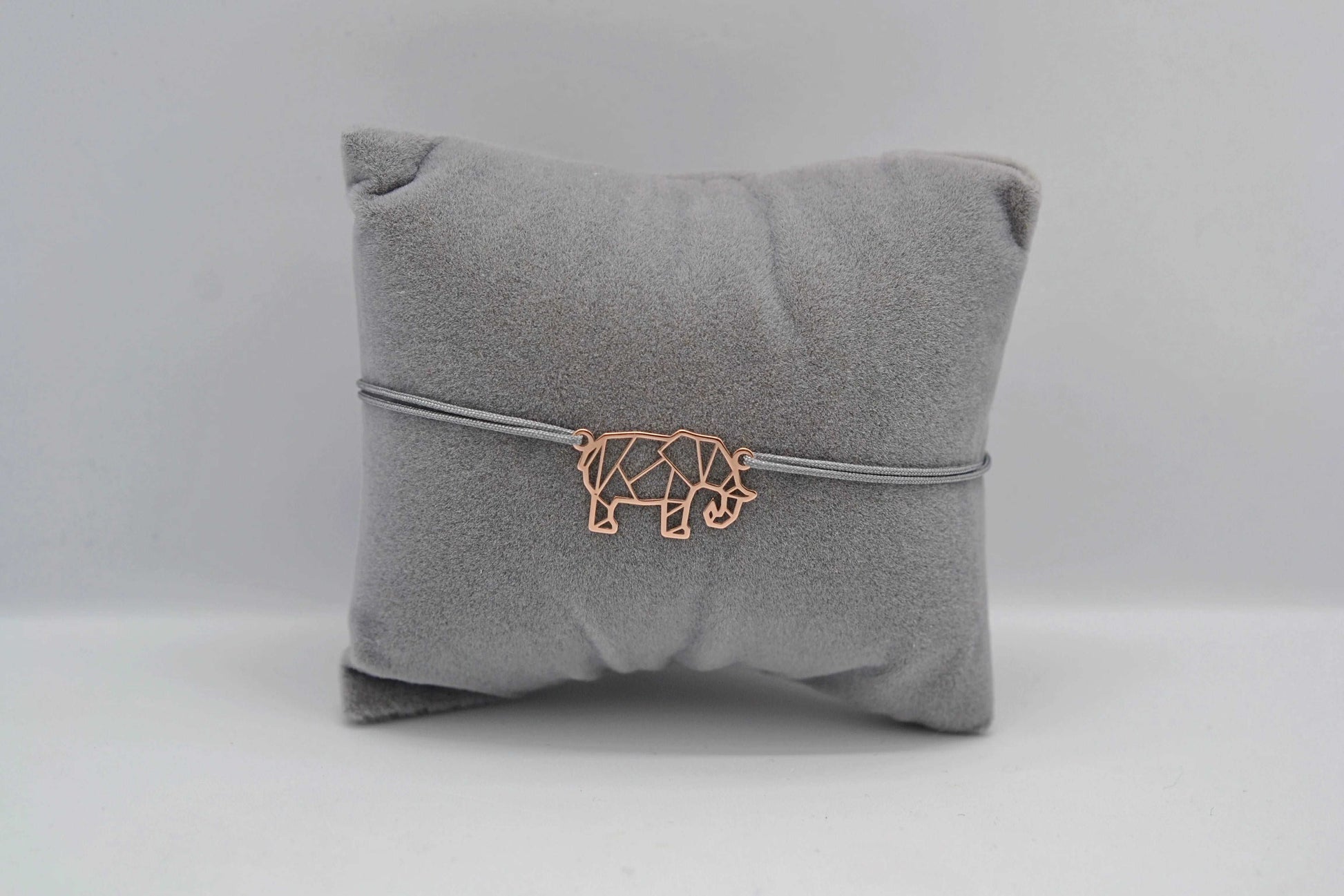 Armband Elefant roségold mit grauem Band auf einem grauen Schmuckkissen