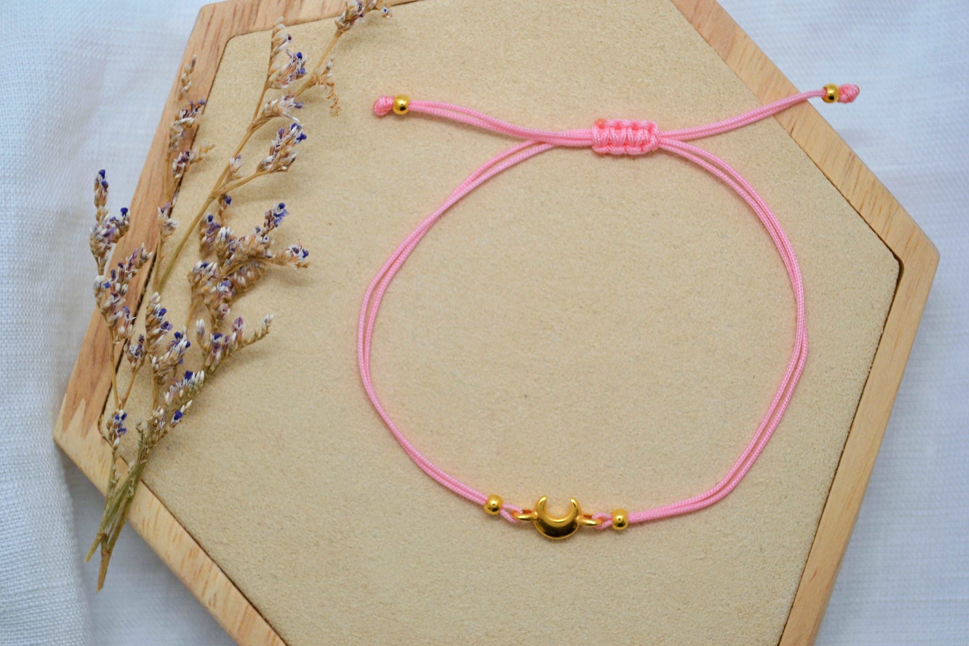 Goldenes Mond Armband mit rosa Band auf einem Holz Sechseck