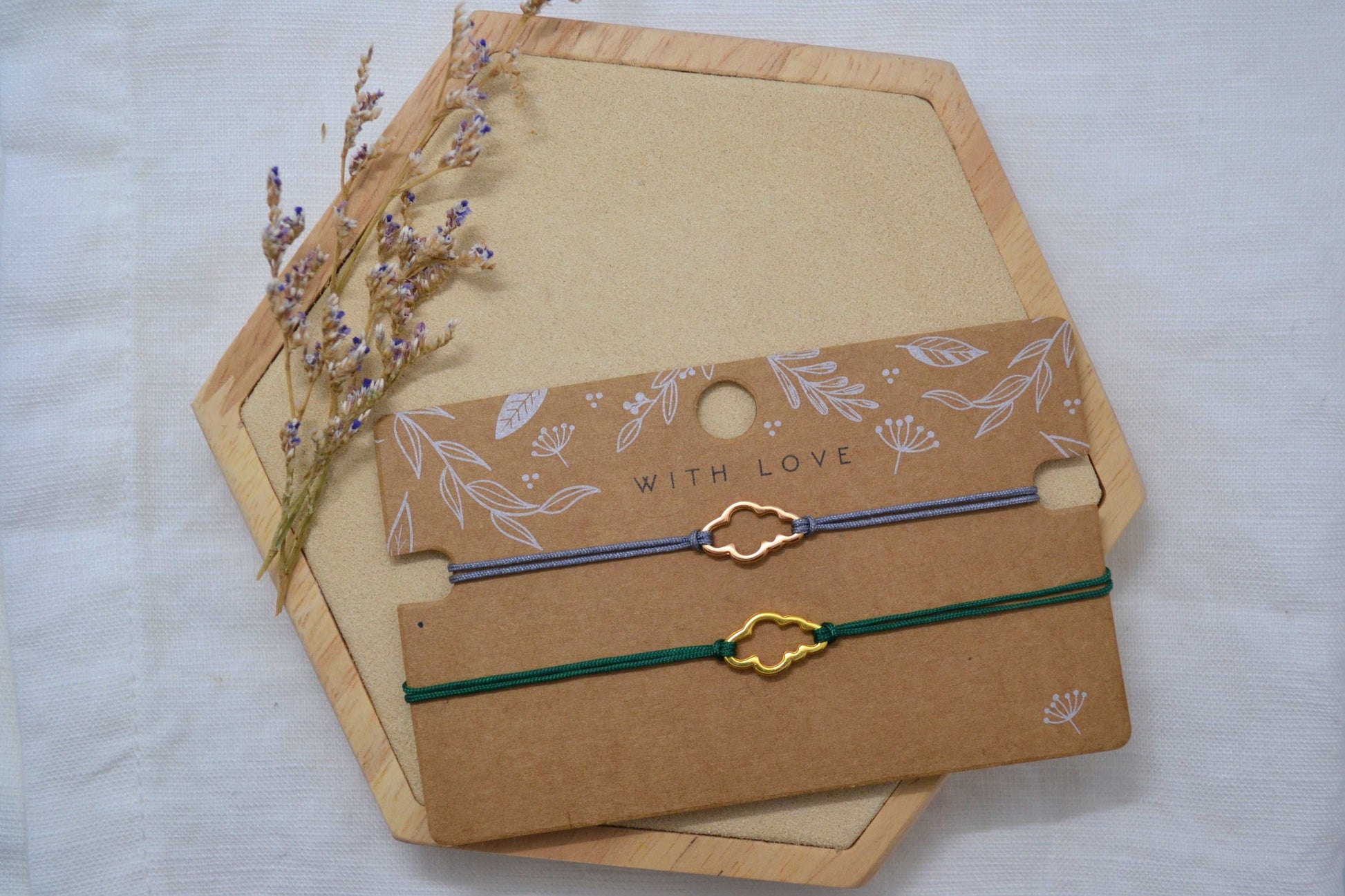 Wolke Armband gold mit grünem Band und roségold mit grauem Band auf einer braunen Schmuckkarten