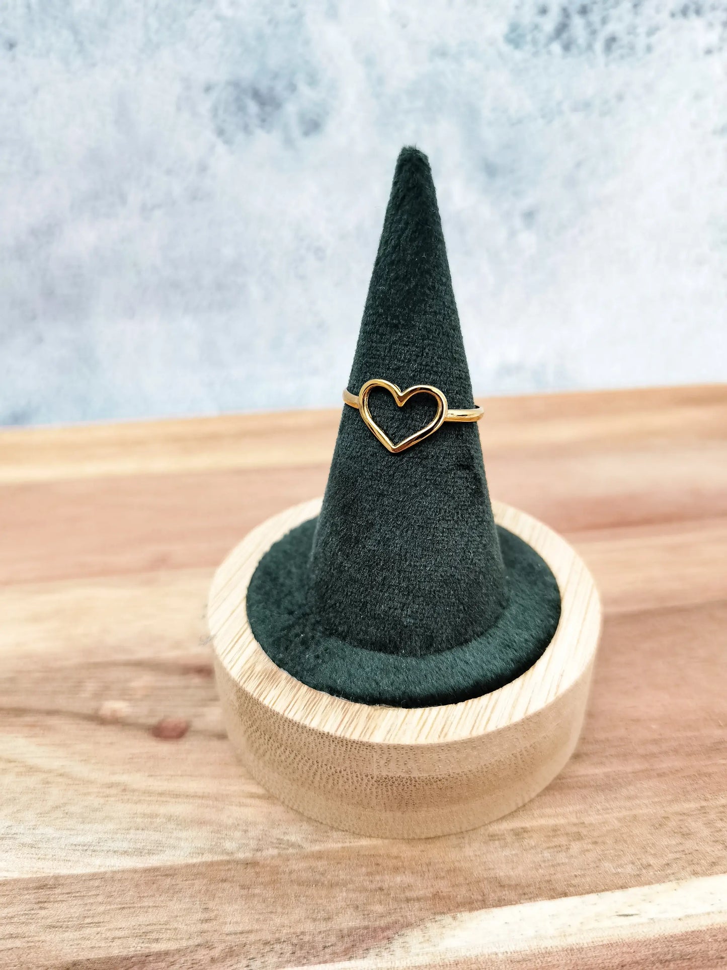 Goldener Herzring fotografiert auf grünem Schmuckhalter mit Holzfuß