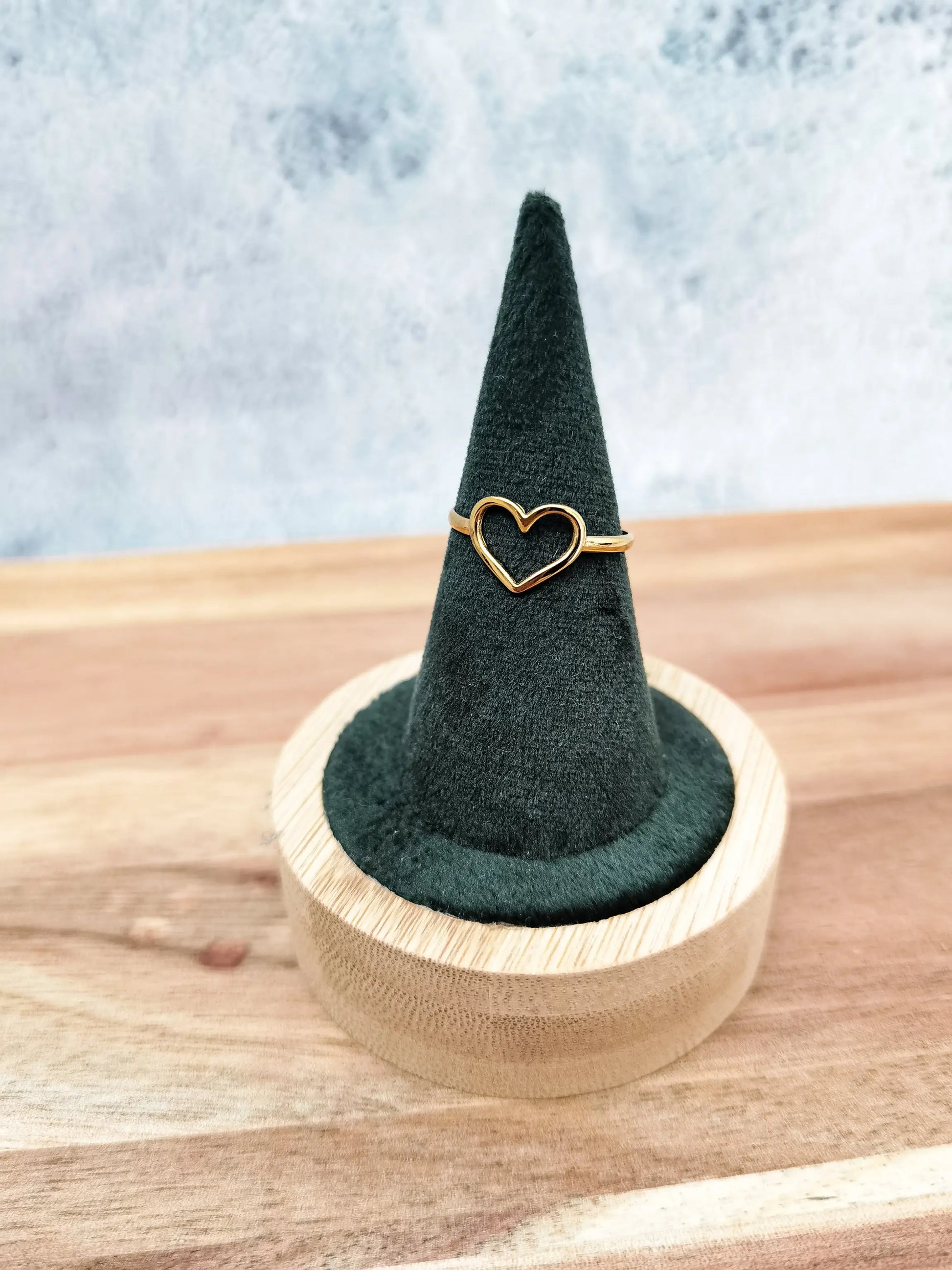 Goldener Herzring fotografiert auf grünem Schmuckhalter mit Holzfuß