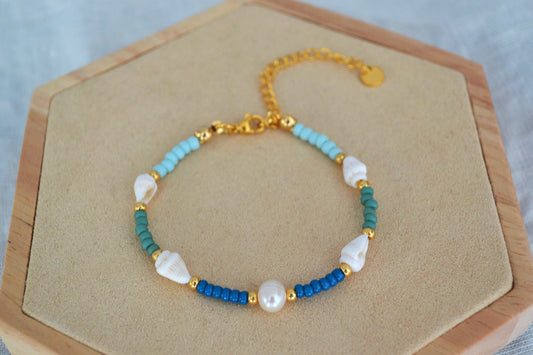Nahaufnahme eines sommerlichen Muschel Armbands mit Süßwasserperle, vier Muscheln sowie Glasperlen in blau, grün und gold