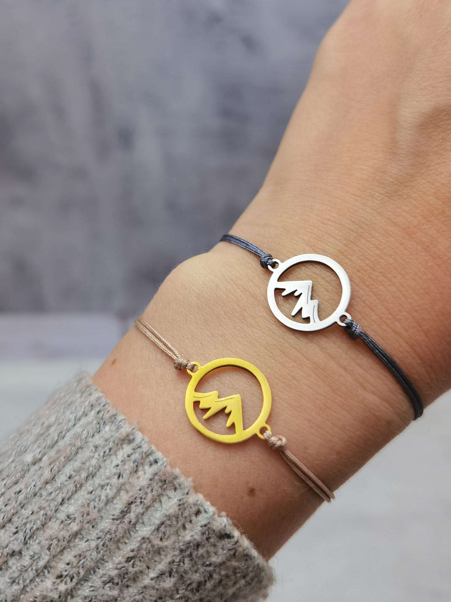 Nahaufnahme Tragefoto Berg Armband gold mit beigem Band und silber mit grauem Band