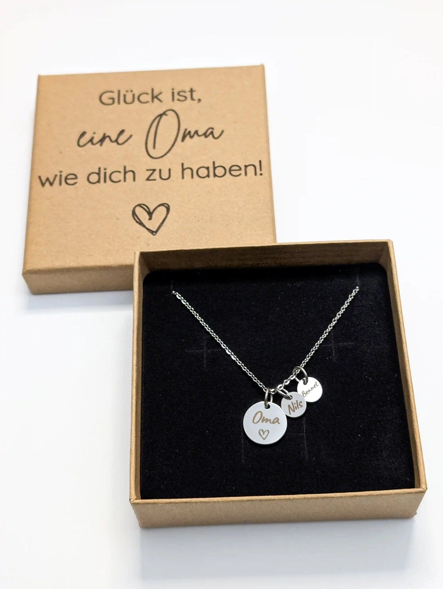 Personalisierte Oma Kette aus Edelstahl in silber mit gravierten Namensanhängern, präsentiert in einer gravierten Geschenkbox aus Kraftkarton mit dem Spruch „Glück ist, eine Oma wie dich zu haben!“ – perfektes Geschenk für Oma.