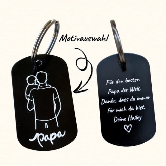 Schwarzer Schlüsselanhänger für Papa. Links Darstellung der Vorderseite eine Line-Art Gravur eines Vaters mit einem kleinen Kind auf dem Arm, darunter der Text "papa". Rechts Darstellung der Rückseite mit Gravur "Für den besten Papa der Welt. Danke, dass du immer für mich da bist. Deine Hailey". Darunter ein Herz