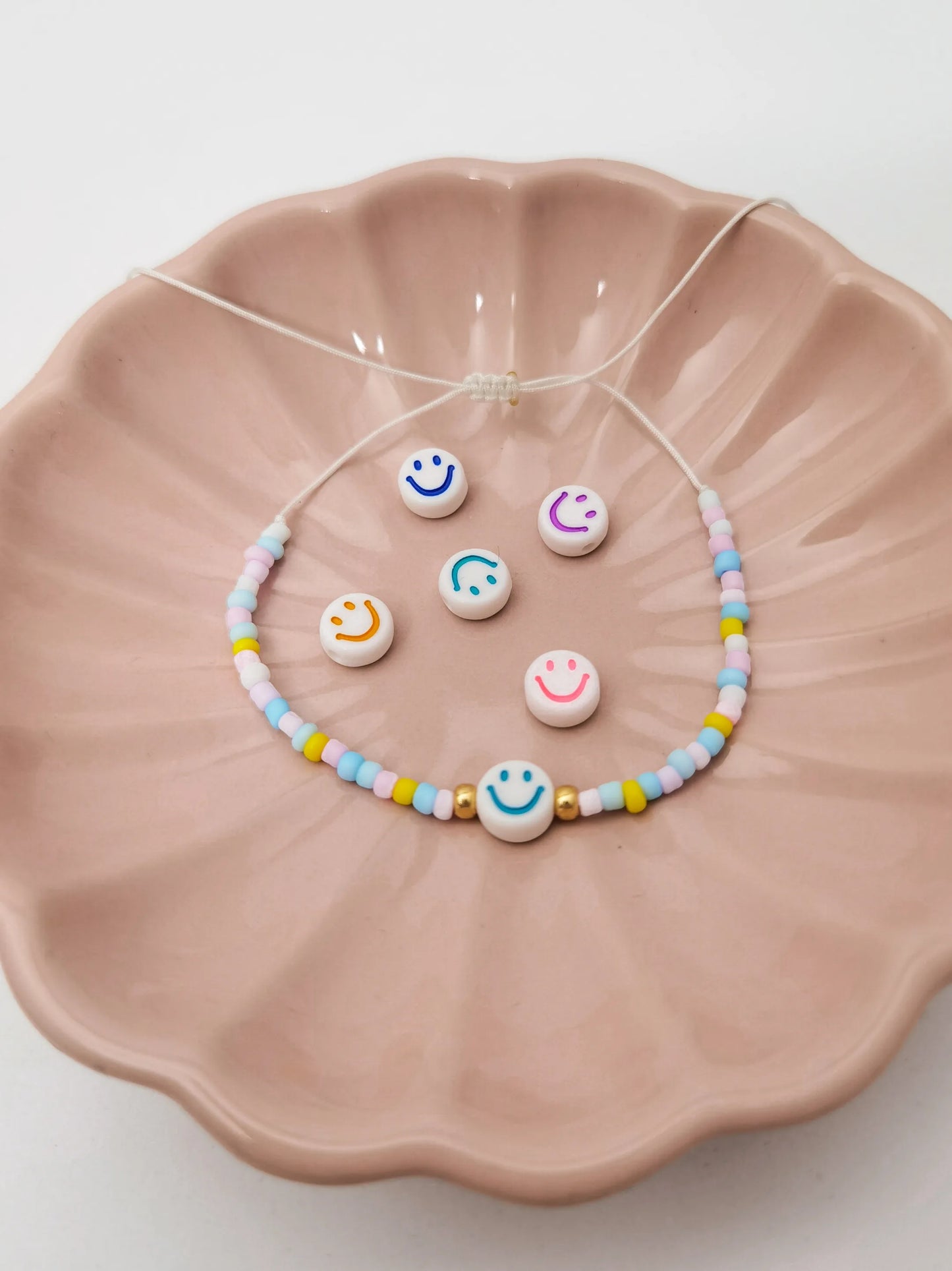 Smiley Armband mit pastellfarbenen Perlen in einer rosa Schale