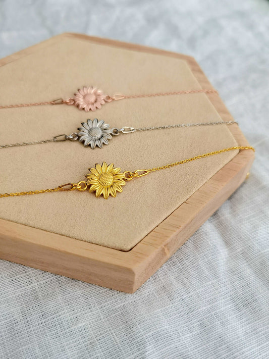 Sonnenblume Armband in gold, silber und roségold auf einem Holz Sechseck vor weißem Hintergrund