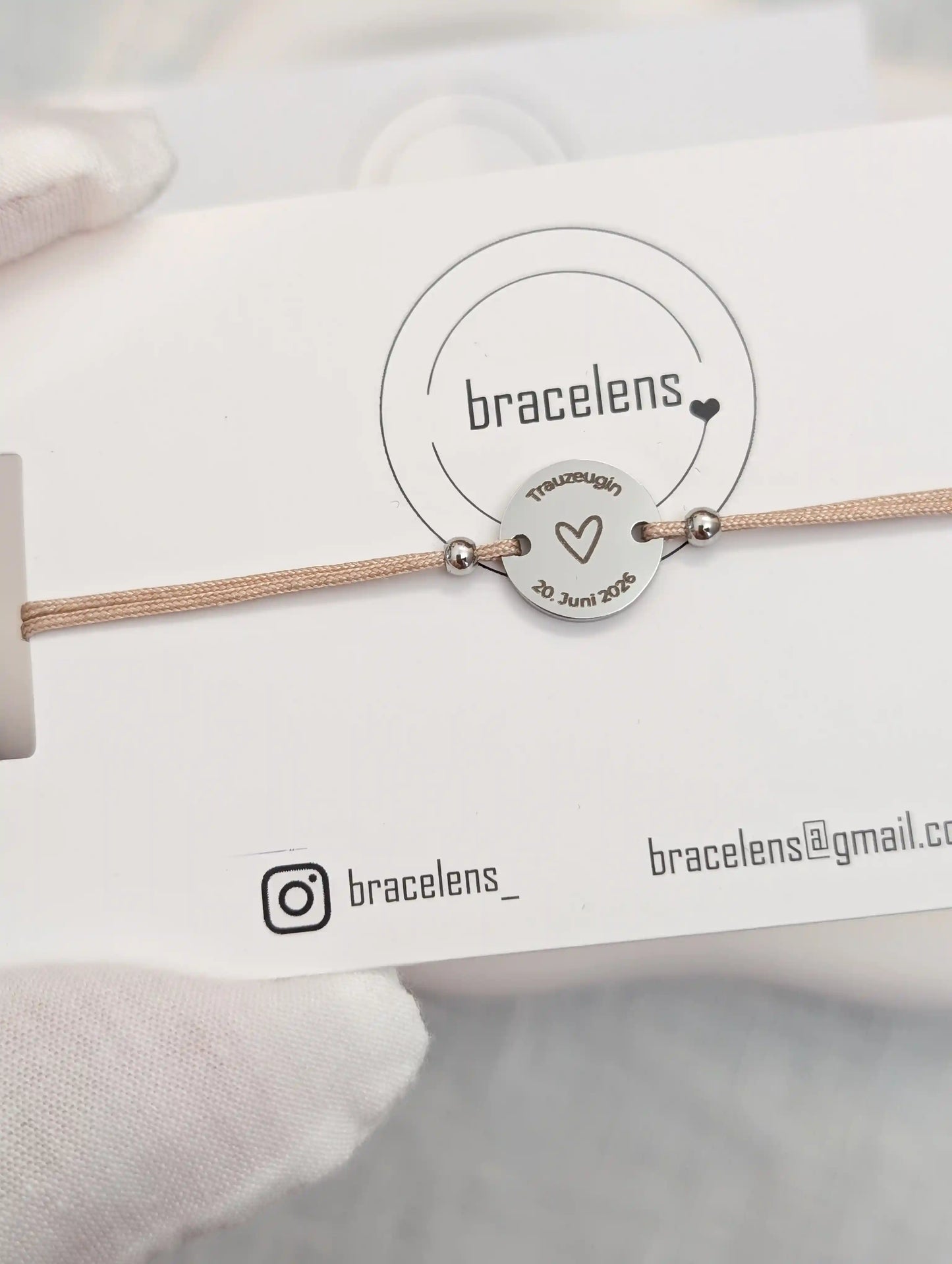 Personalisiertes Trauzeugin Armband mit runder Edelstahl-Gravur auf Schmuckkarte von bracelens, graviert mit Herz, Schriftzug „Trauzeugin“ und Datum, filigranes Armband auf beigem Band