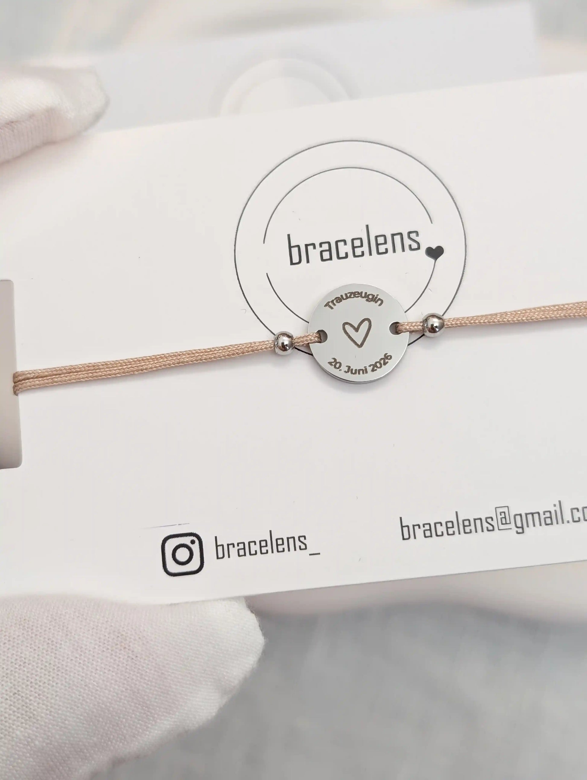 Personalisiertes Trauzeugin Armband mit runder Edelstahl-Gravur auf Schmuckkarte von bracelens, graviert mit Herz, Schriftzug „Trauzeugin“ und Datum, filigranes Armband auf beigem Band